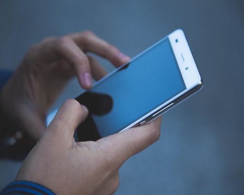 Person holding mobile phone at eye level while sitting comfortably